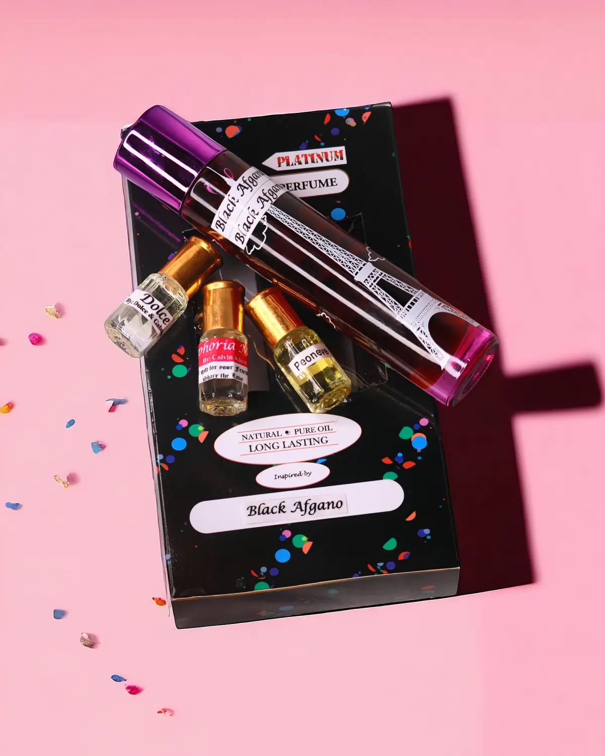 A large bottle of perfume oil resting on its printed box on a pink background